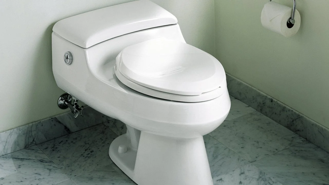 Modern white toilet on marble floor, representing reliable plumbing solutions for Oviedo homeowners, emphasizing toilet clog repair services by R&A Industries.