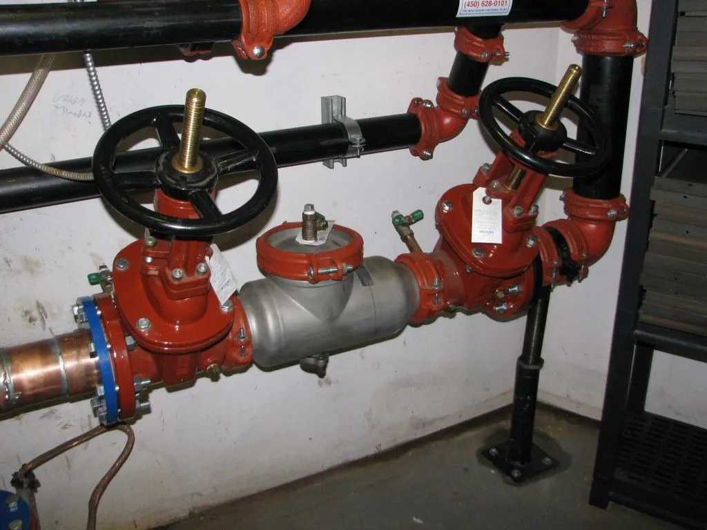 Complex plumbing with red pipes and black valves, Oviedo, FL. Backflow testing system for commercial building water supply.