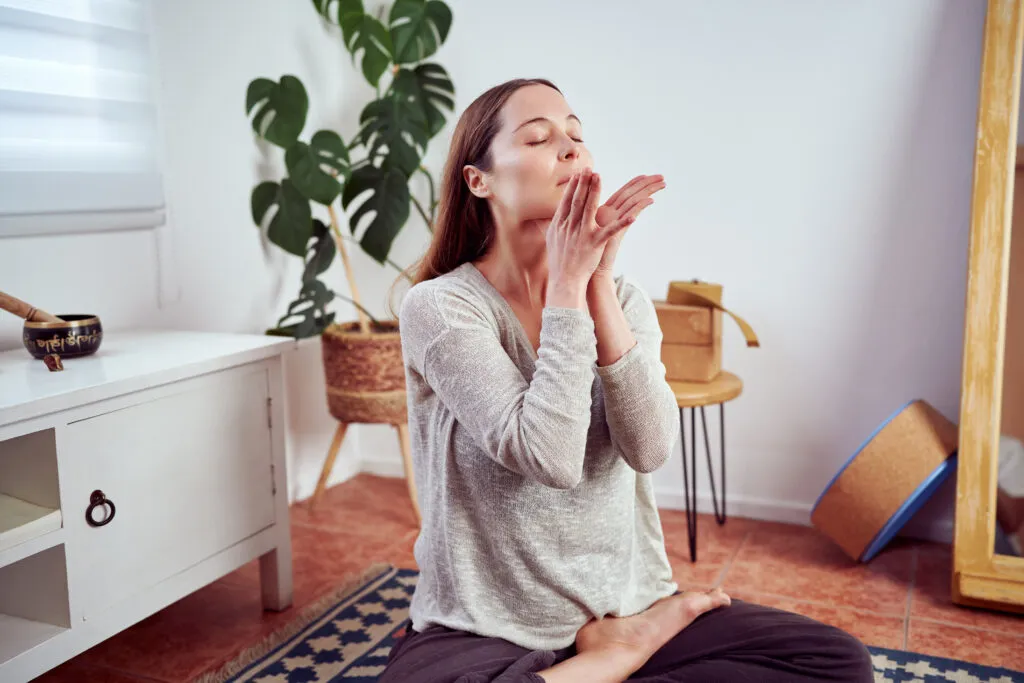 Woman meditating for Air Cleaning System benefits, promoting indoor air quality and wellness in a serene space.