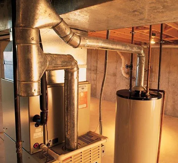 Furnace and water heater in a basement. Ductwork connects the furnace to the chimney. Heating system in Oviedo, FL.