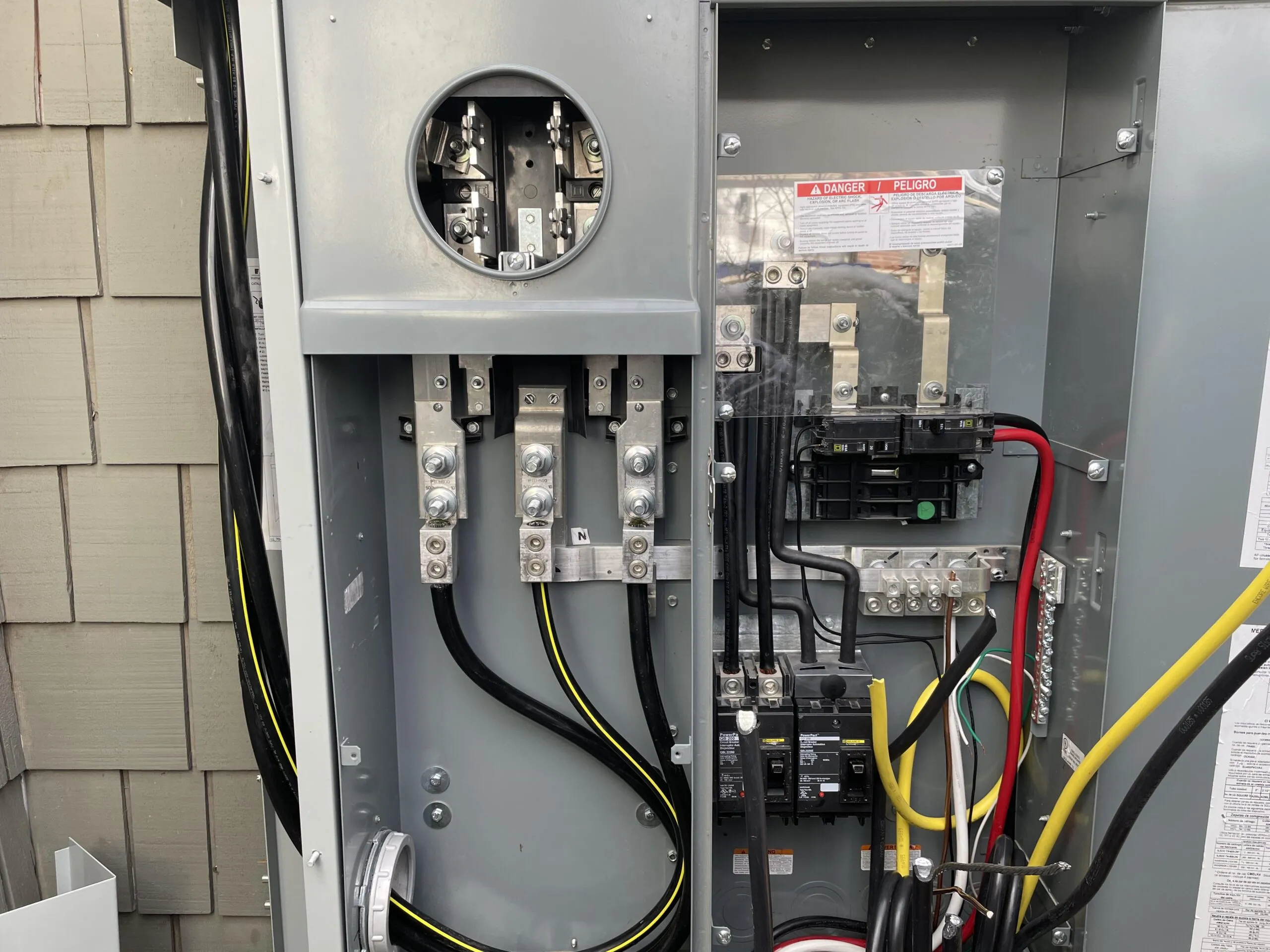 Electrical panel installation view. Close up of an open grey electrical box showing wiring and circuit breakers.