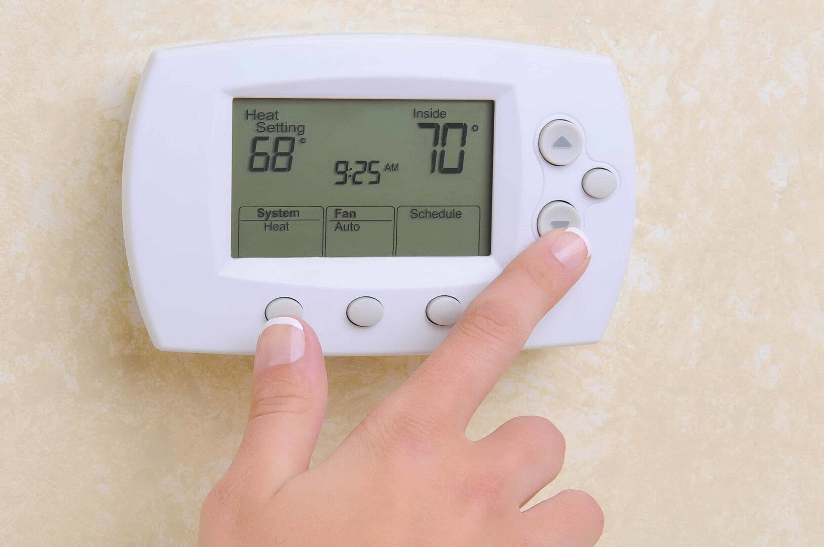 Thermostat displaying heat setting of 68°F and inside temperature of 70°F, with a hand adjusting the controls, emphasizing heating system maintenance and calibration services by R&A Industries.