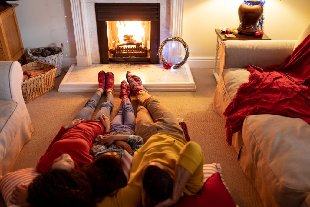 Family relaxing by a cozy fireplace during Christmas, emphasizing warmth and togetherness, relevant to furnace maintenance in Oviedo, FL.