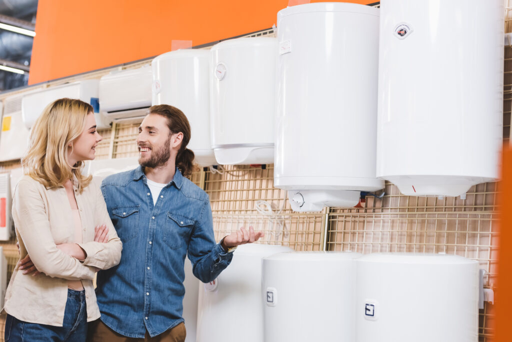 Couple discussing water heater options in a home improvement store, surrounded by various models, emphasizing R&A Industries' water heater installation services in Oviedo.