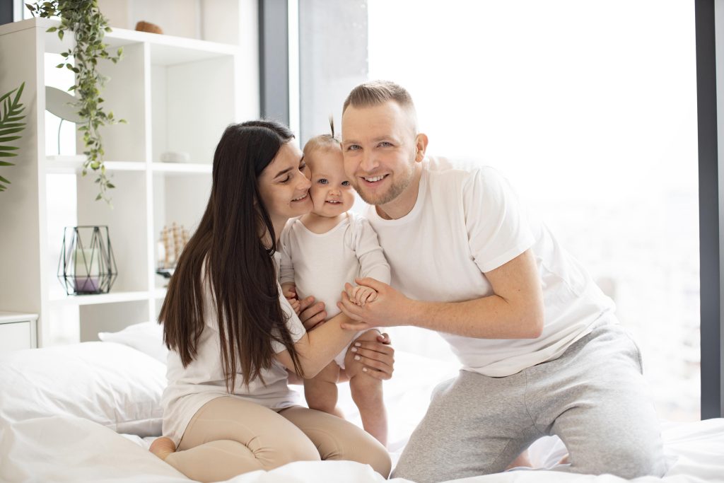 Protect your family with Whole Home Surge Protection. Happy family portrait with mother, father, and baby smiling in Oviedo, FL home.